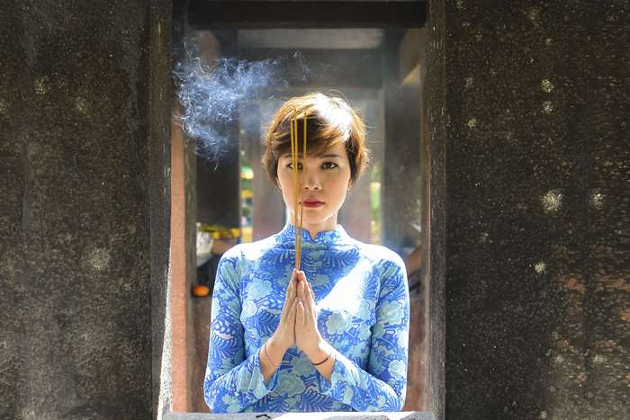 Woman praying with incense sticks in Vietnam