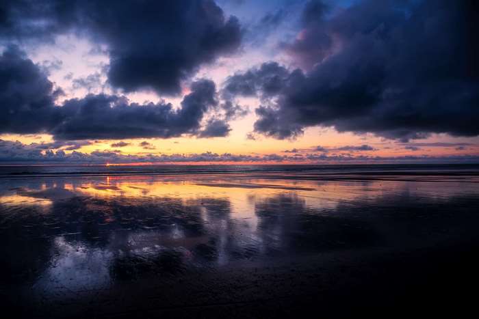 Sunset over the ocean with dramatic clouds and reflections