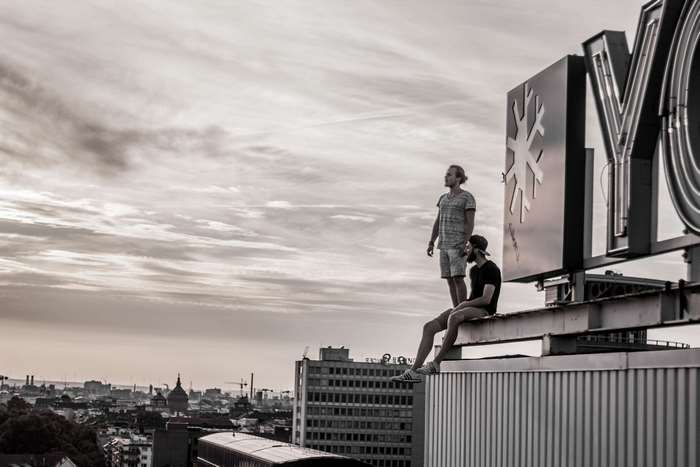 Two young men on a rooftop with city skyline
