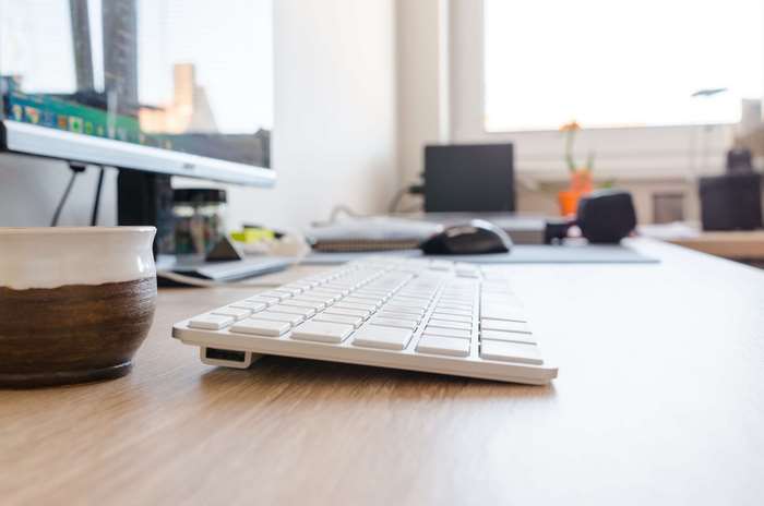 Desk with computer, keyboard, mouse, and cup