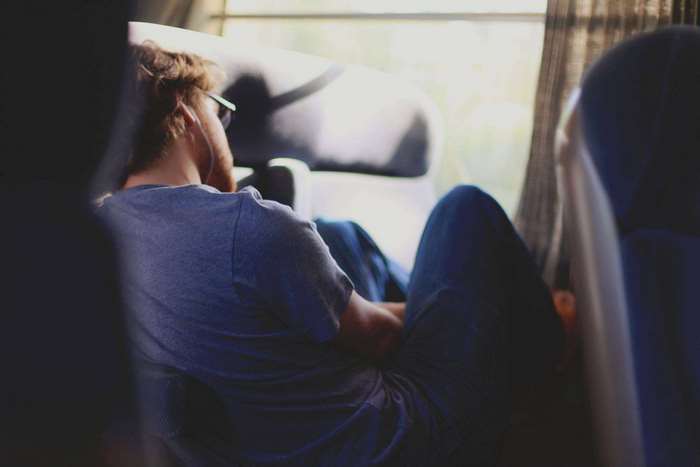 Man wearing earphones sitting by a train window