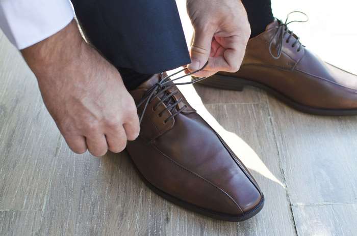 Man tying brown leather dress shoes