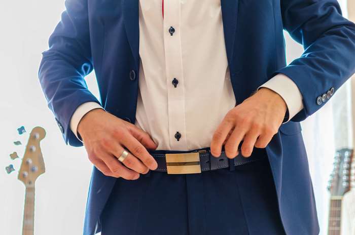Man in a suit adjusting his belt