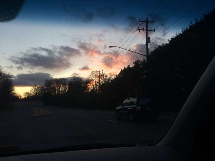 Car driving on road at sunset with power lines