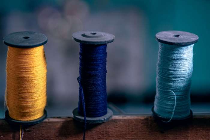 Three spools of thread in yellow, blue, and light blue