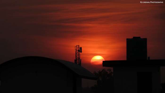 Sunset over buildings with cell tower