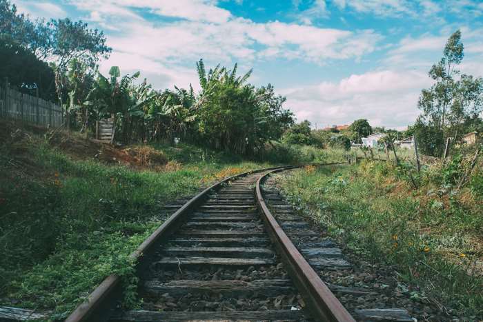 Railroad tracks curving through a grassy landscape under a cloudy sky