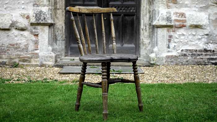 Antique wooden chair in front of a stone building