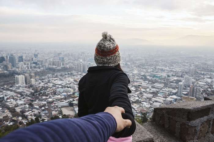 Couple holding hands overlooking a city
