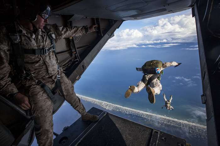 Marines jump from a plane over the ocean