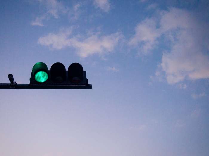 Green traffic light against a blue sky with clouds
