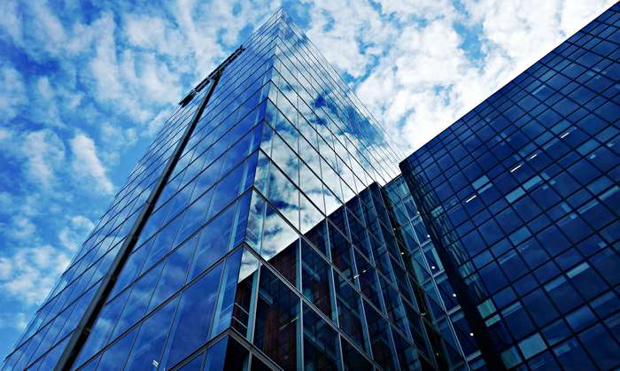 Modern glass skyscrapers reflecting blue sky and clouds