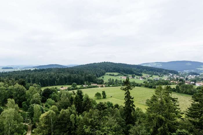 Green valley with forests and houses under cloudy sky