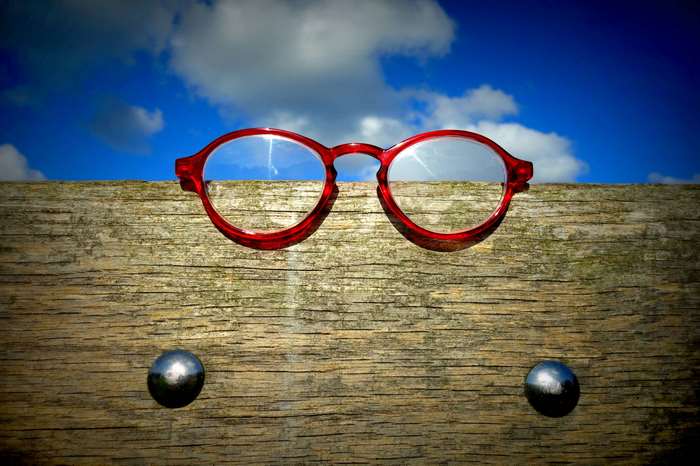 Red glasses on a wooden fence with blue sky