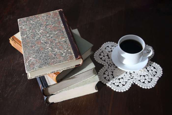 Stack of antique books with coffee cup on lace placemat