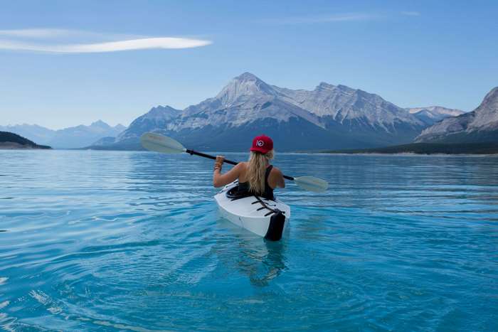 Woman kayaking on a lake with mountains