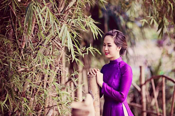Woman in traditional purple dress near bamboo