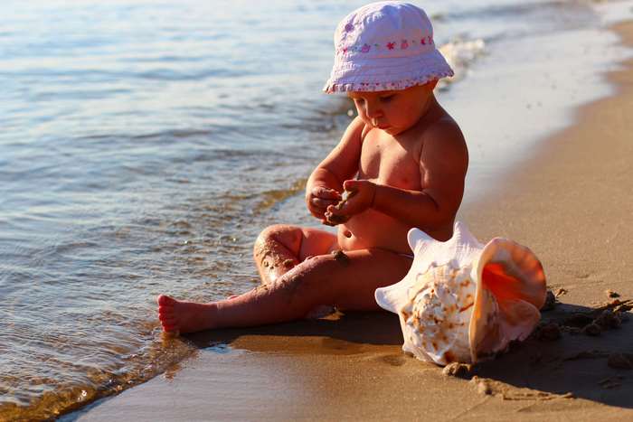 Toddler playing with seashells on the beach 4K