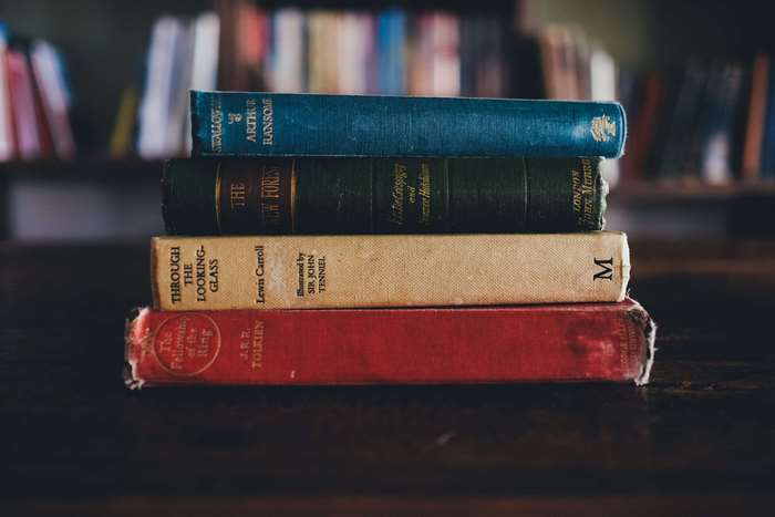Stack of old books including The Fellowship of the Ring and Through the Looking-Glass