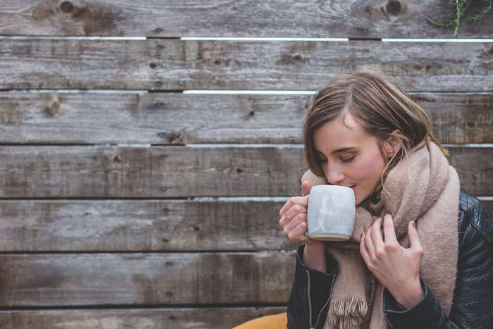Woman drinking from a mug in front of a wooden wall 4K