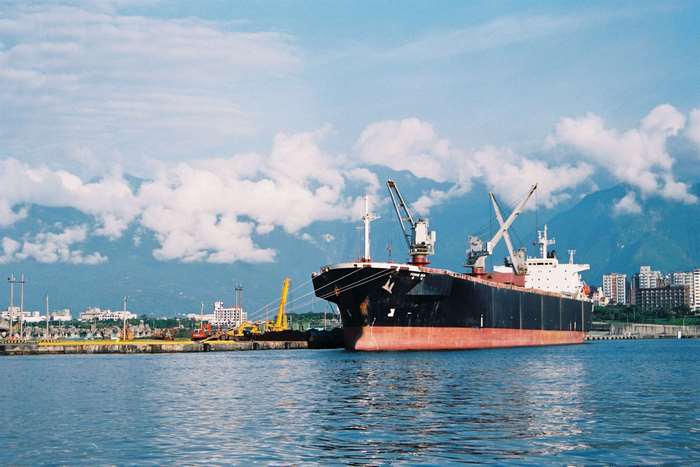 Cargo ship docked in a port with cityscape and mountains