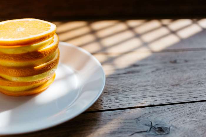 Stack of orange slices on a white plate on a wooden table