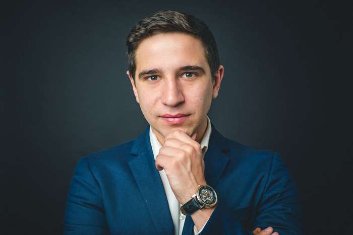Man in a blue suit with hand on chin
