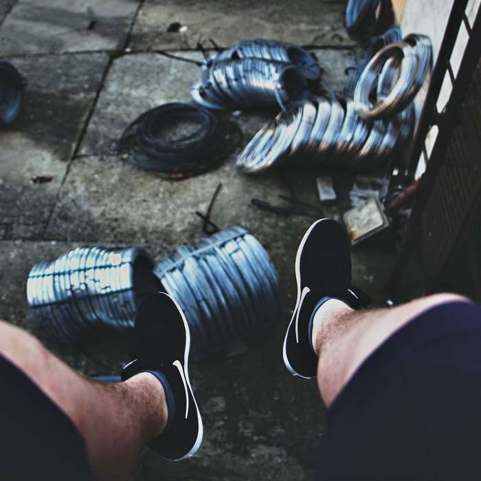 Man wearing Nike shoes sitting near wire coils