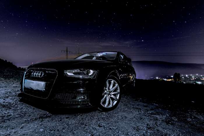Black Audi A4 Avant parked under starry night sky