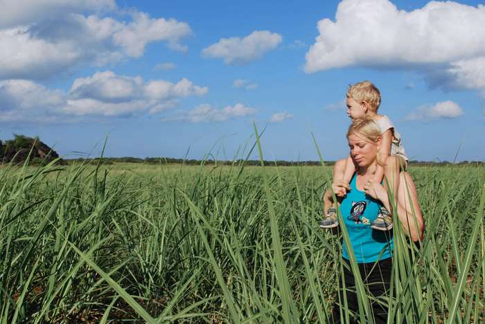 Woman carrying son on shoulders in sugar cane field
