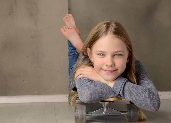 Smiling Girl Relaxing on Skateboard Indoors