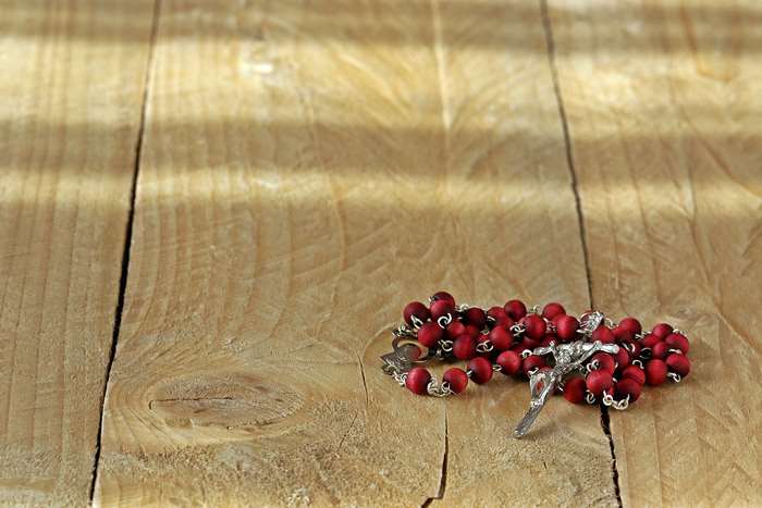 Rosary beads with crucifix on wooden surface 4K