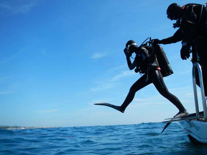 Scuba divers jumping from a boat into the sea