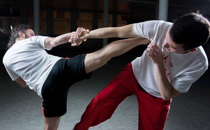 Two men practicing martial arts with a kick
