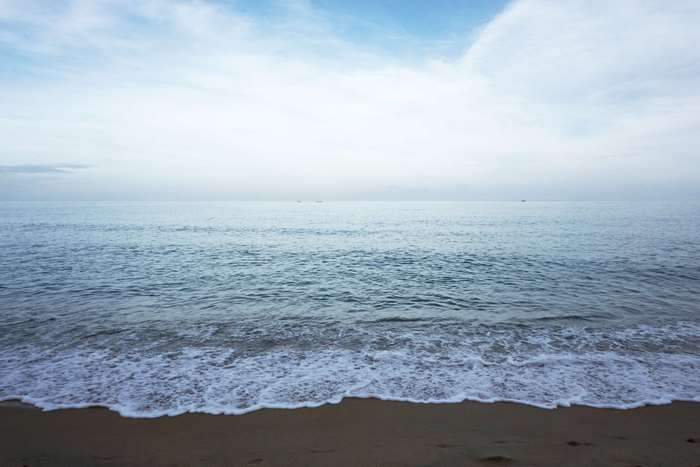 Ocean waves on a sandy beach under a cloudy sky