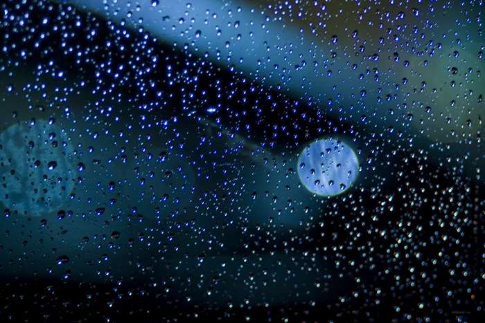 Raindrops on glass with blue bokeh lights