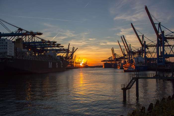 Container ships and cranes at Hamburg port during sunset