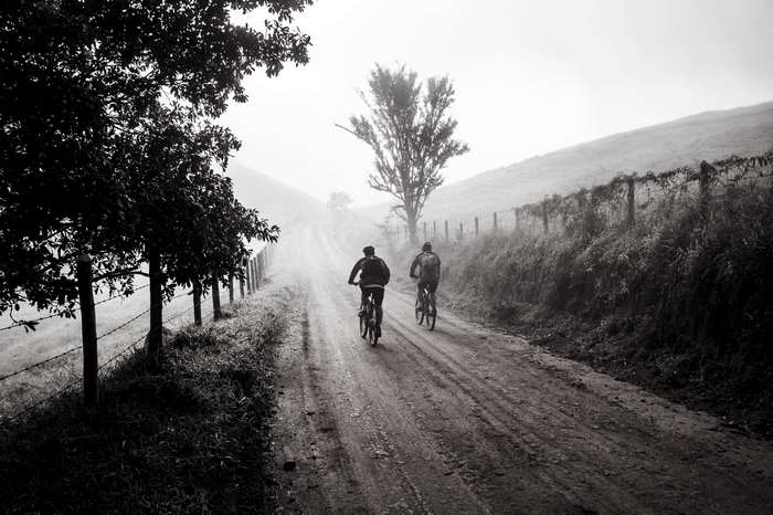 Two people cycling on a foggy dirt road