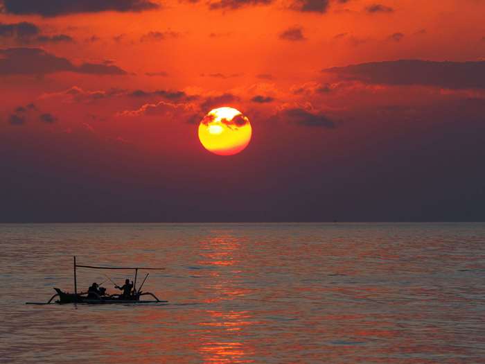 Fishermen in a boat at sunset over the sea