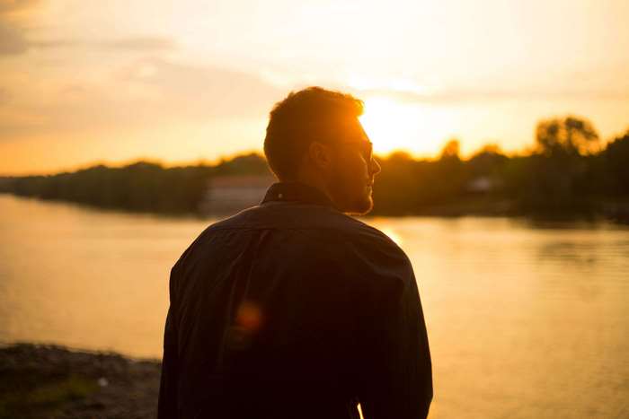 Man looking at sunset over a river