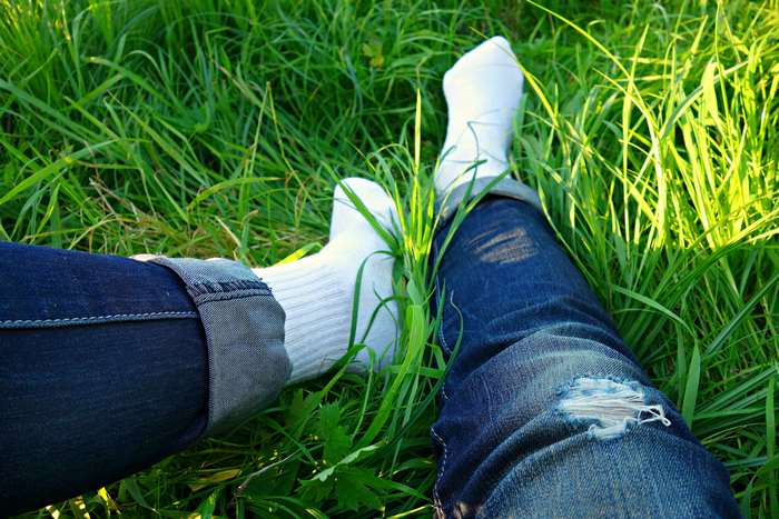 Two people in jeans and socks relaxing in grass