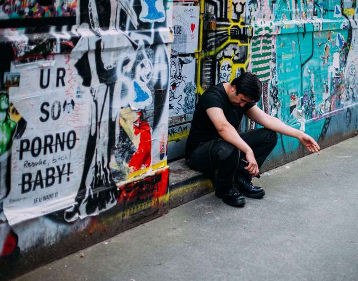 Man sitting by graffiti wall