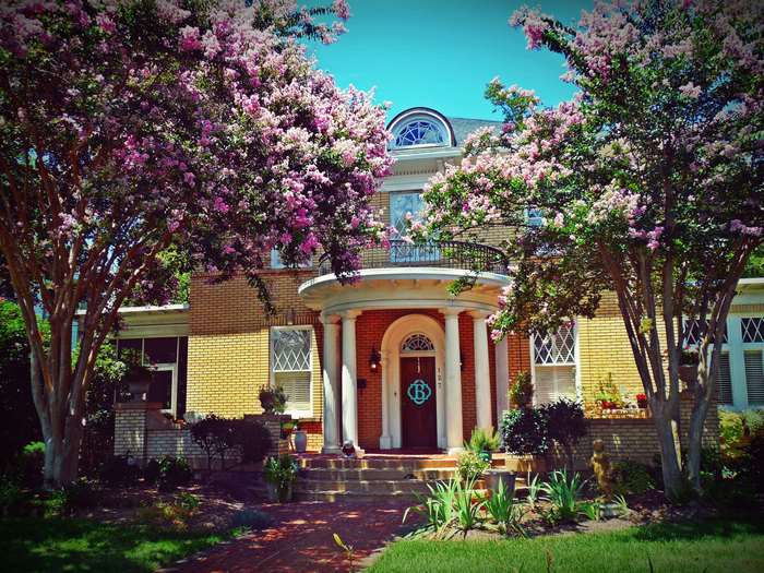 Yellow brick house with blooming trees and balcony