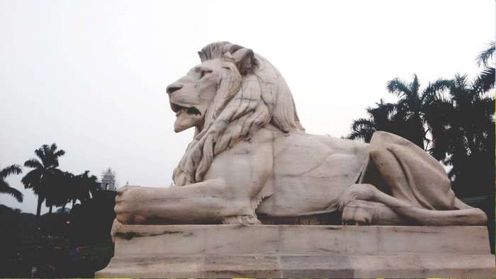 Marble lion statue in Kolkata with palm trees
