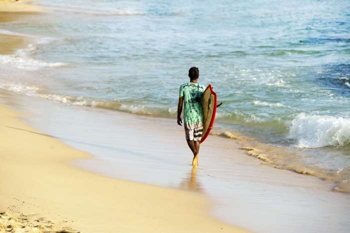 Man walking on beach with surfboard