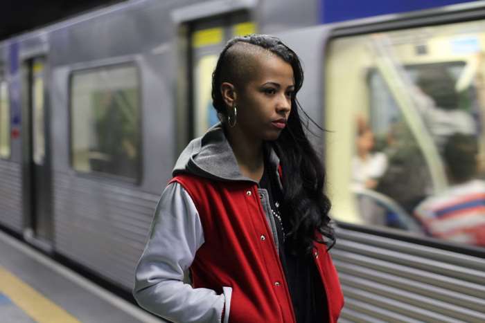 Woman with shaved head and red jacket on subway platform