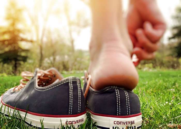 Converse sneakers on grass with a foot