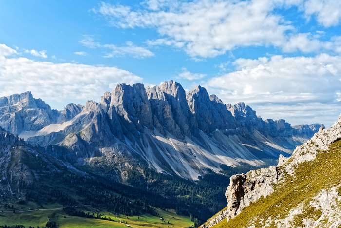 Jagged mountain range under a blue sky with clouds