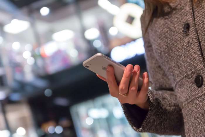 Woman holding an iPhone in a blurred commercial establishment