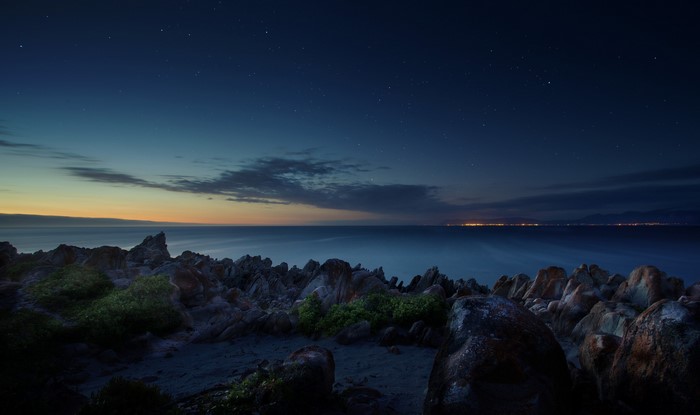 Rocky coastline at night with ocean and stars